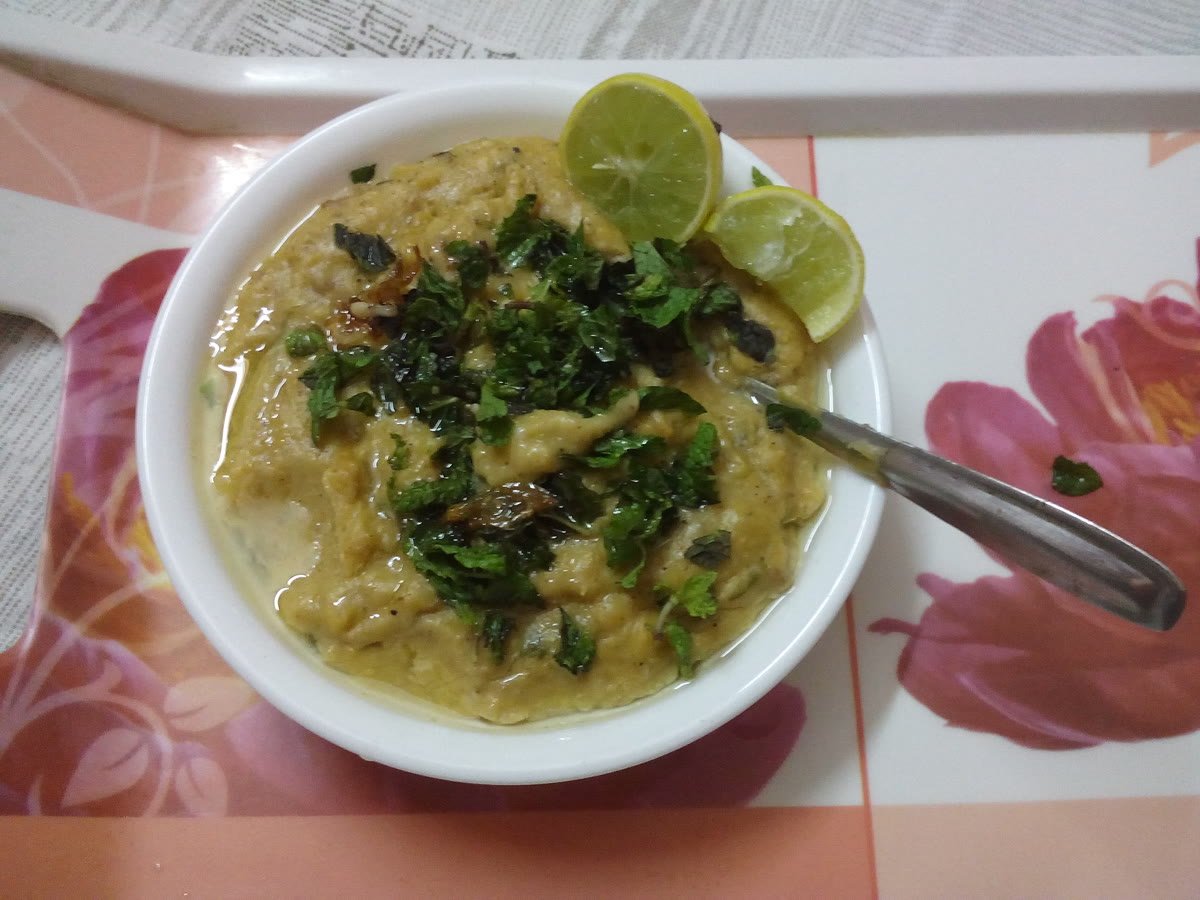 A bowl of Hyderabadi haleem with lime and herbs